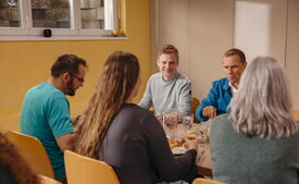 Mehrere Personen sitzen bei einem gemeinsamen Essen an einem Tisch bei der Heilsarmee Affoltern am Albis.