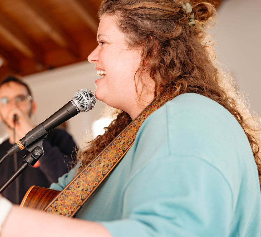 Eine Frau singt mit Gitarre in ein Mikrofon während eines Gottesdienstes der Heilsarmee Affoltern am Albis.
